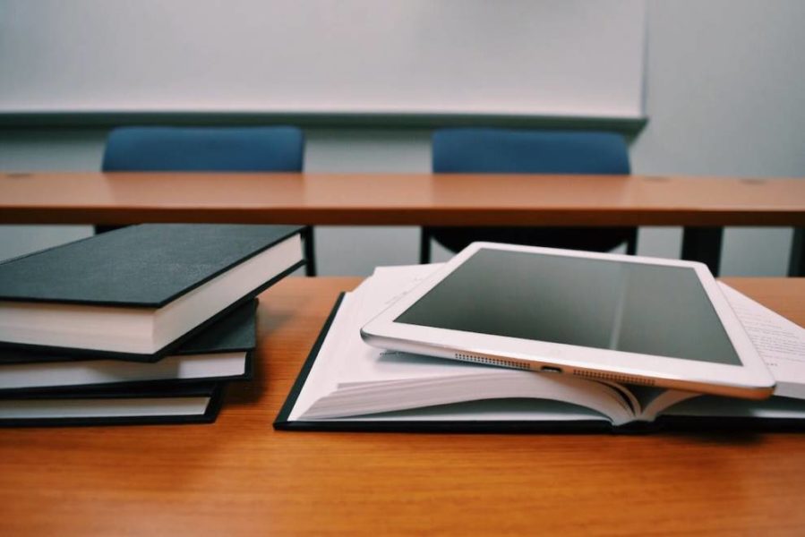 Silver iPad placed on a white book, symbolizing digital education and modern learning resources.