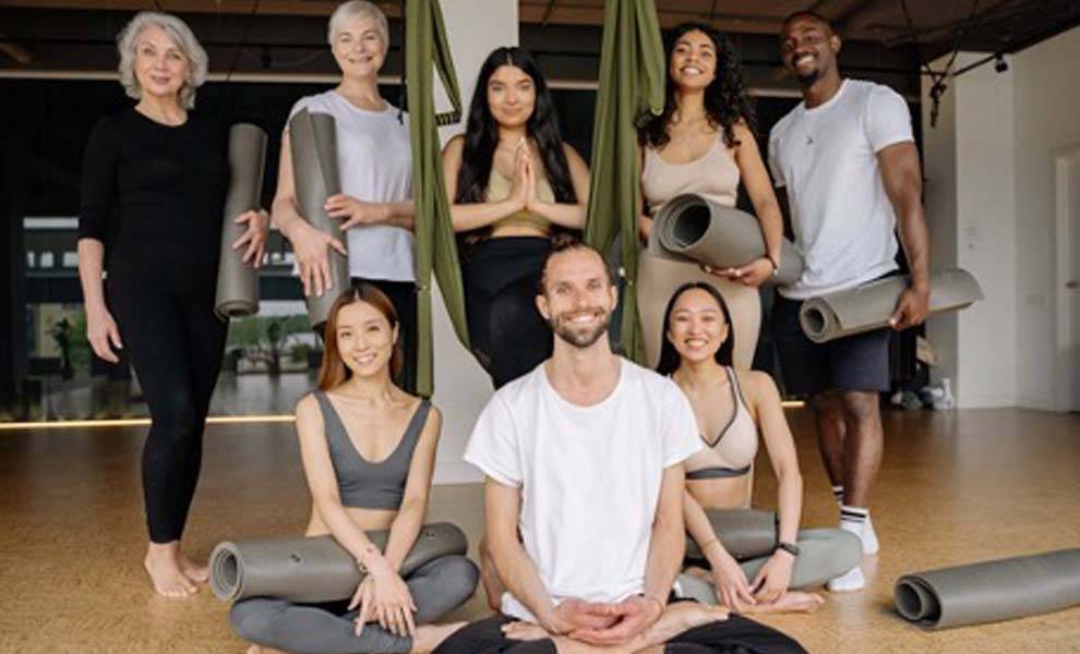 A diverse group of individuals smiling and posing for a photo in a serene yoga studio