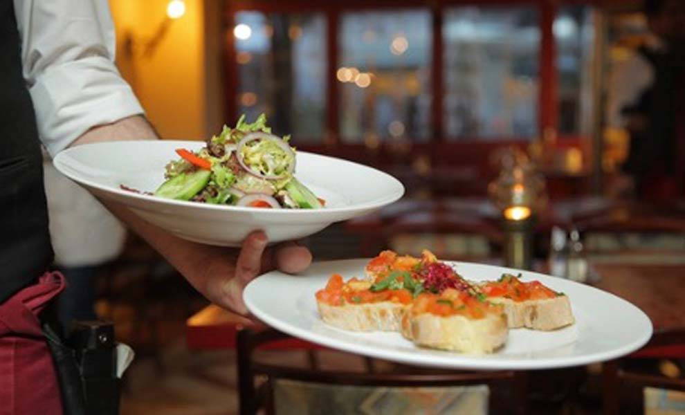 A waiter holding two plates of delicious food, ready to serve hungry customers at a restaurant