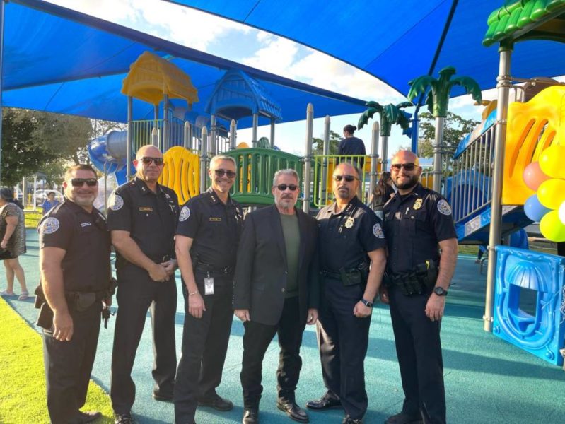 Cinco agentes de policía de Sweetwater parados frente a un parque infantil, garantizando la seguridad y protección