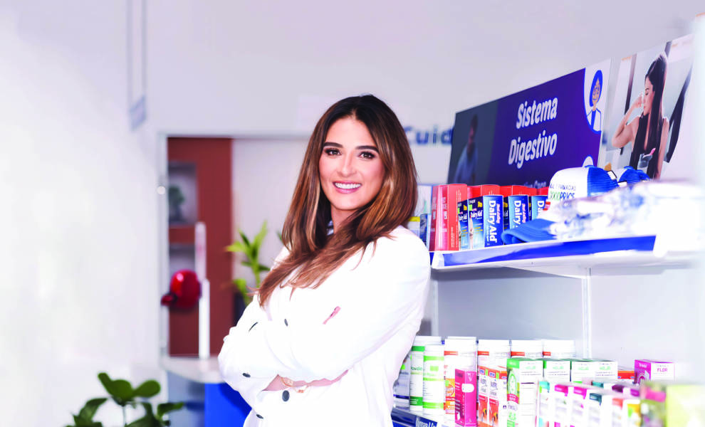 Yessica González con bata de laboratorio apoyada en estante de medicamentos