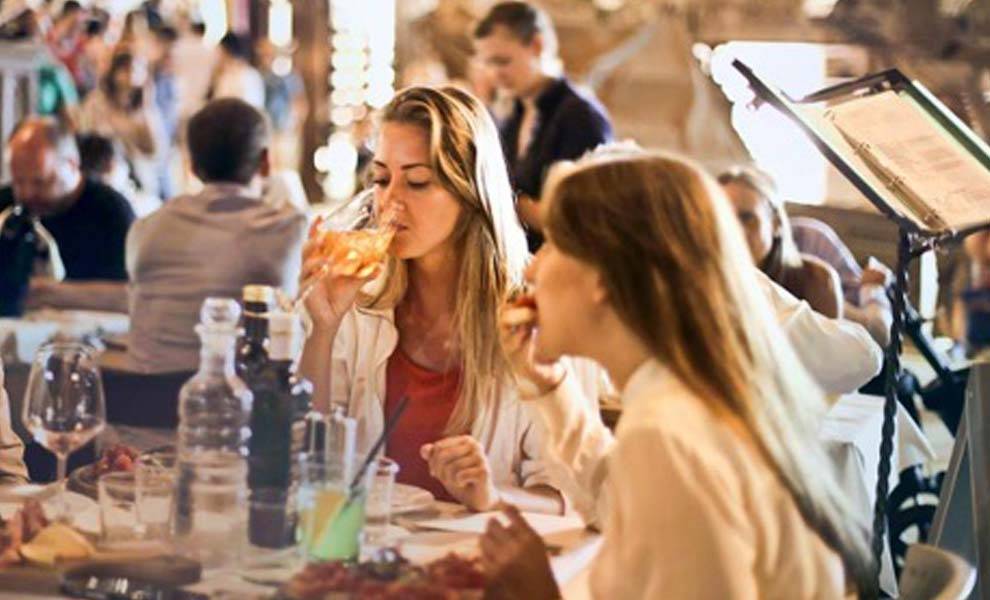 Personas disfrutando de una comida en un restaurante, saboreando deliciosas comidas y bebidas en un ambiente animado