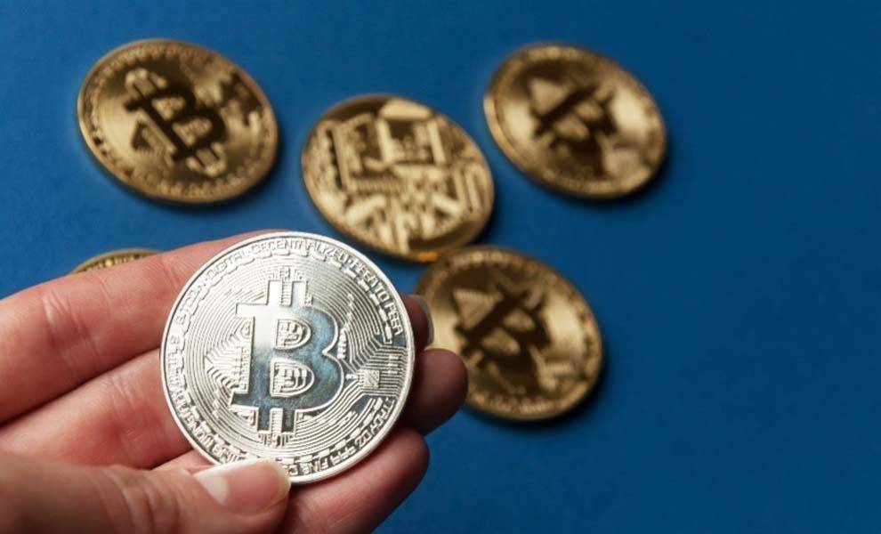 Bitcoin is on a hand with a few bitcoins at the background