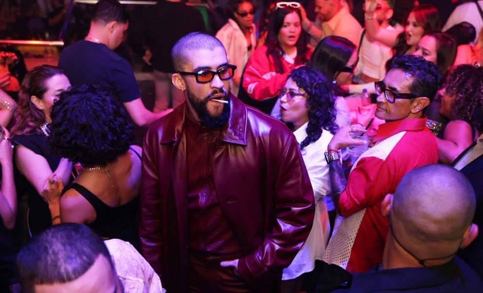 Un hombre con una chaqueta roja y gafas de sol sonriendo en una fiesta