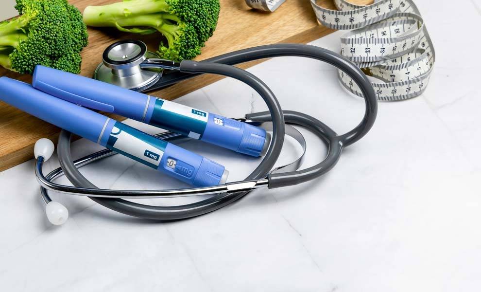 A stethoscope, measuring tape, and blue pen on a cutting board, tools for precise measurements in a medical setting.