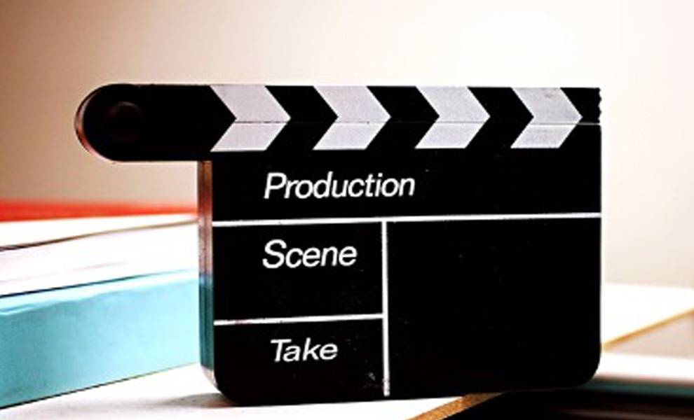 Un badajo de película apoyado sobre un escritorio rodeado de libros y papeles.