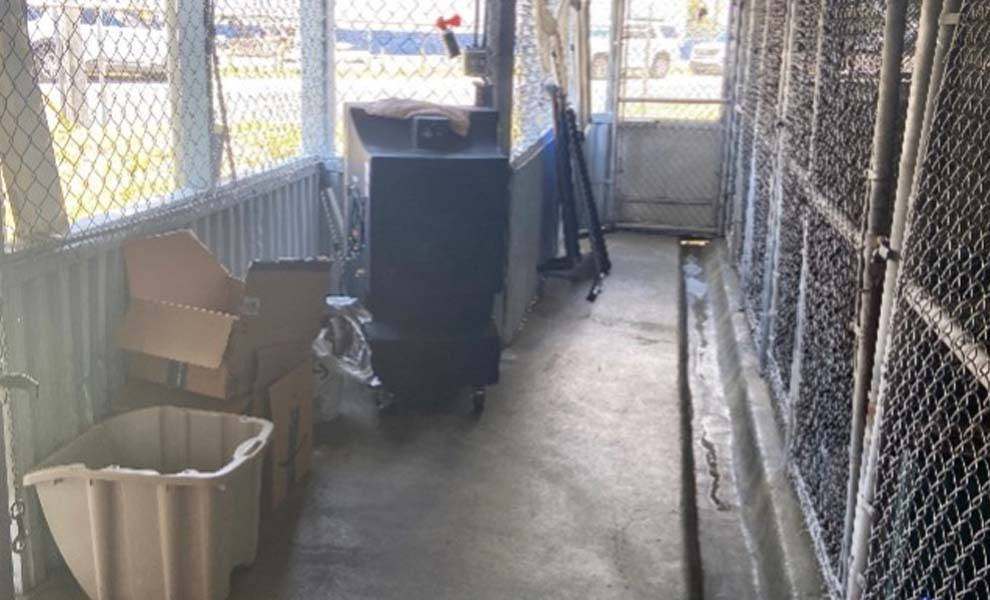 A room with a fence and a box on the ground, showcasing a simple yet intriguing outdoor scene.