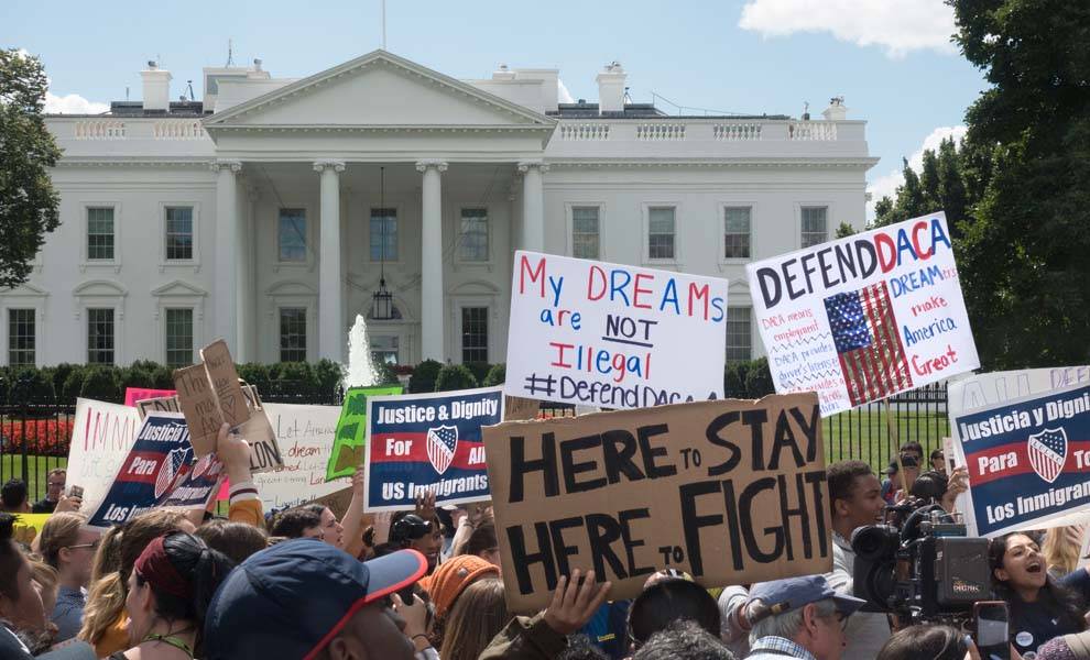 Protesters holding signs in front of the White House, advocating for change and justice.
