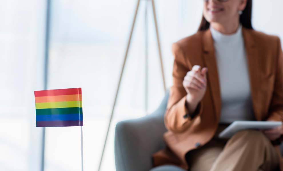 A woman sitting in a chair with a rainbow flag in front of her