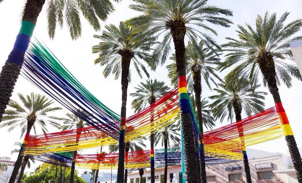 Cintas de colores que cuelgan entre palmeras creando un dosel vibrante.