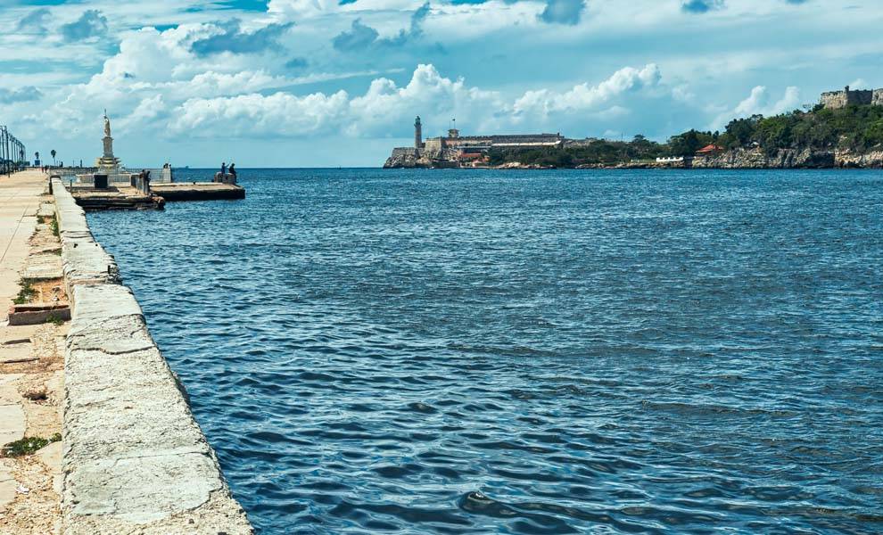 Vista panorámica al mar con muelle y faro al fondo.
