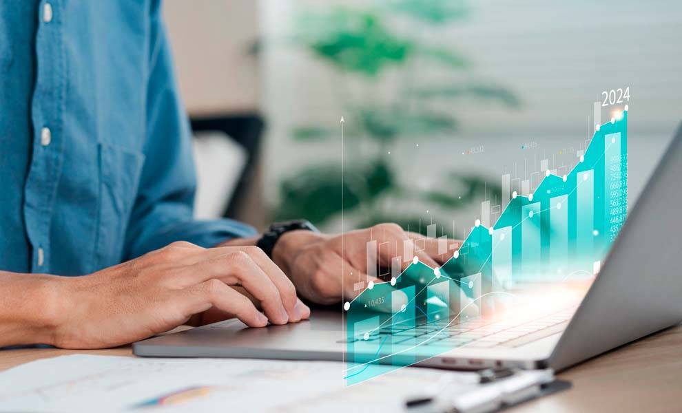 Un hombre escribiendo en una computadora portátil con un gráfico mostrado.