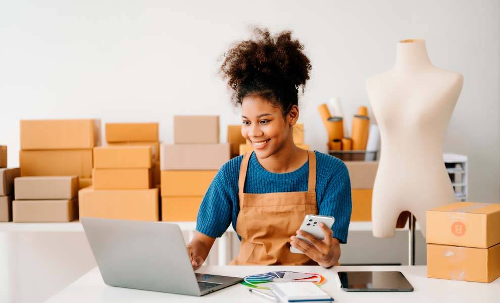 A woman in an apron typing on a laptop.