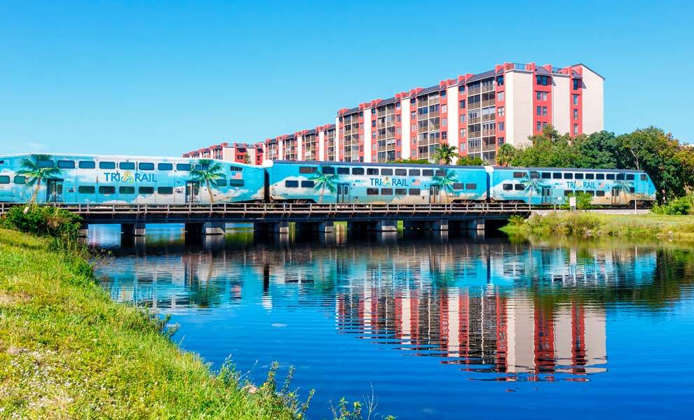 Un tren cruzando un puente frente a un edificio.