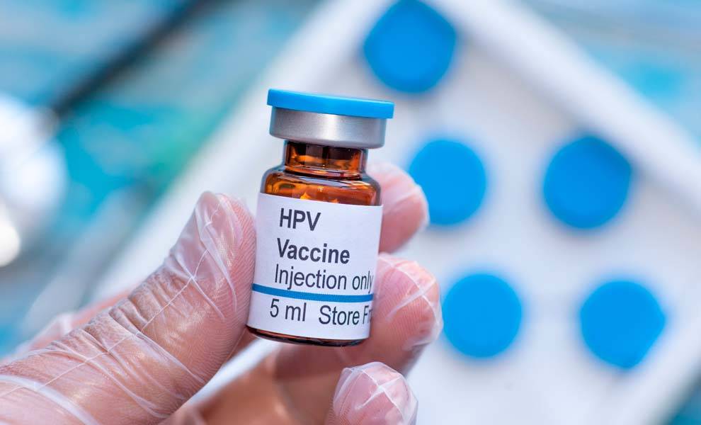 A person holding a vial of HPV vaccine.
