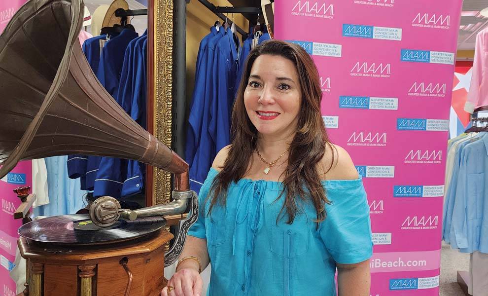 Woman in blue shirt standing by vintage gramophone.