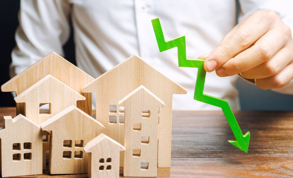 A man holding a wooden house with a green arrow pointing upward