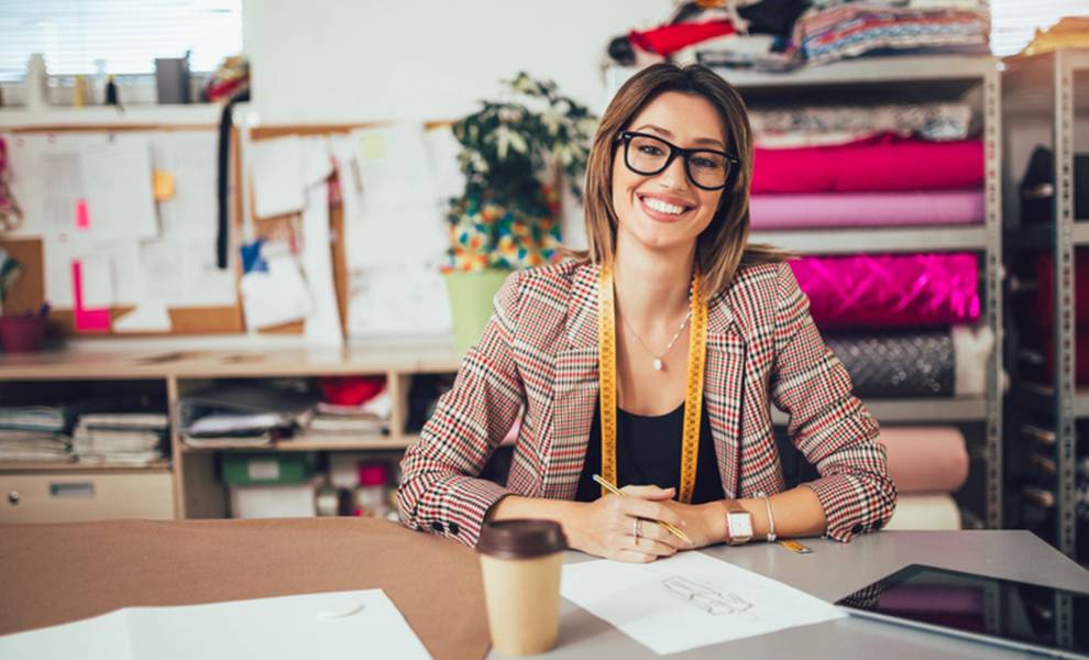 Una mujer con gafas sentada en un escritorio con una computadora portátil, concentrada en su trabajo.