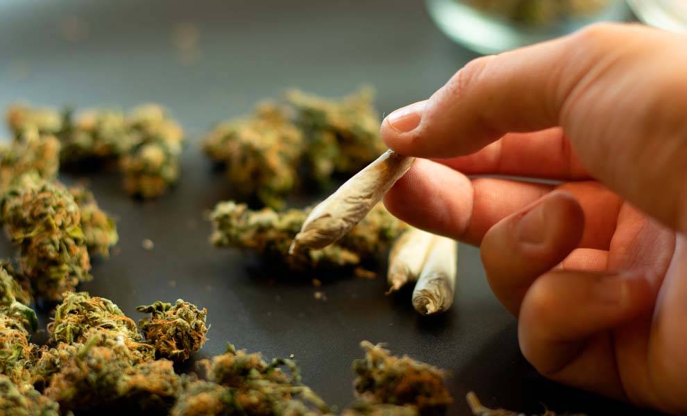 A person holding a marijuana cigarette.