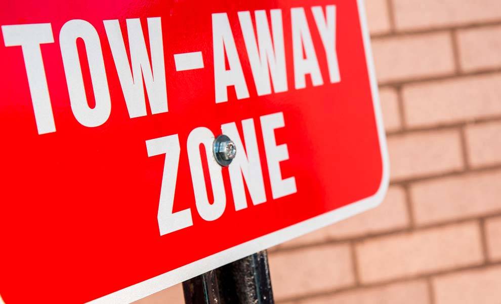 Red and white sign with text Tow Away Zone.
