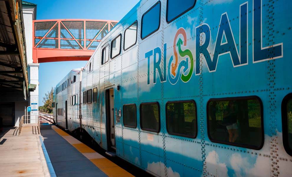 Tri-Rail parked at station with bridge in background.