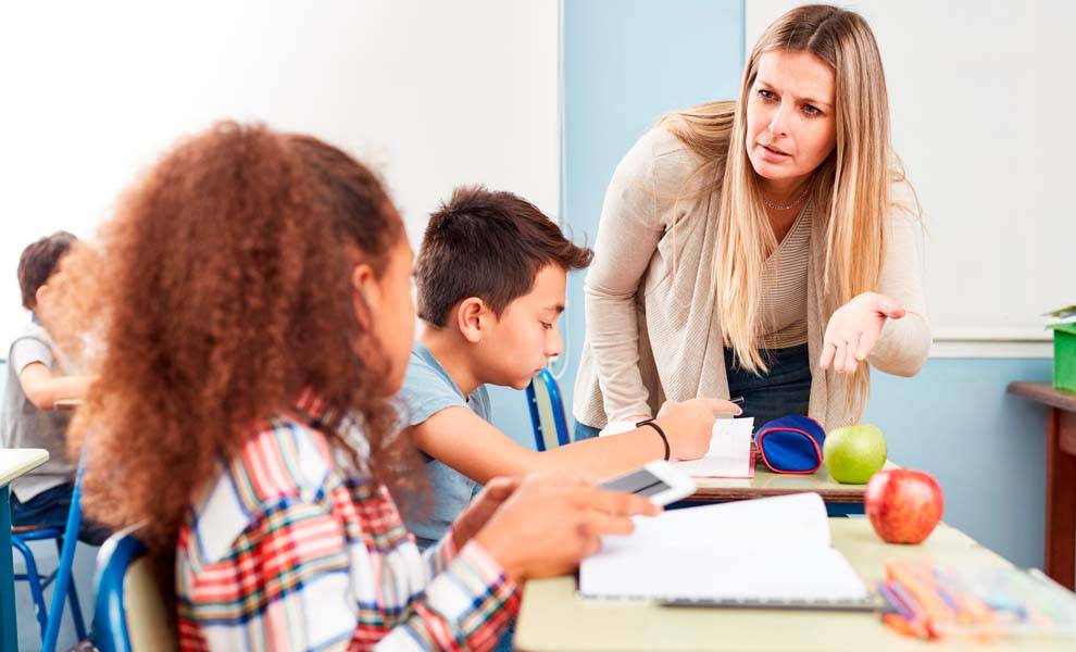 A teacher taking cell phone from student.