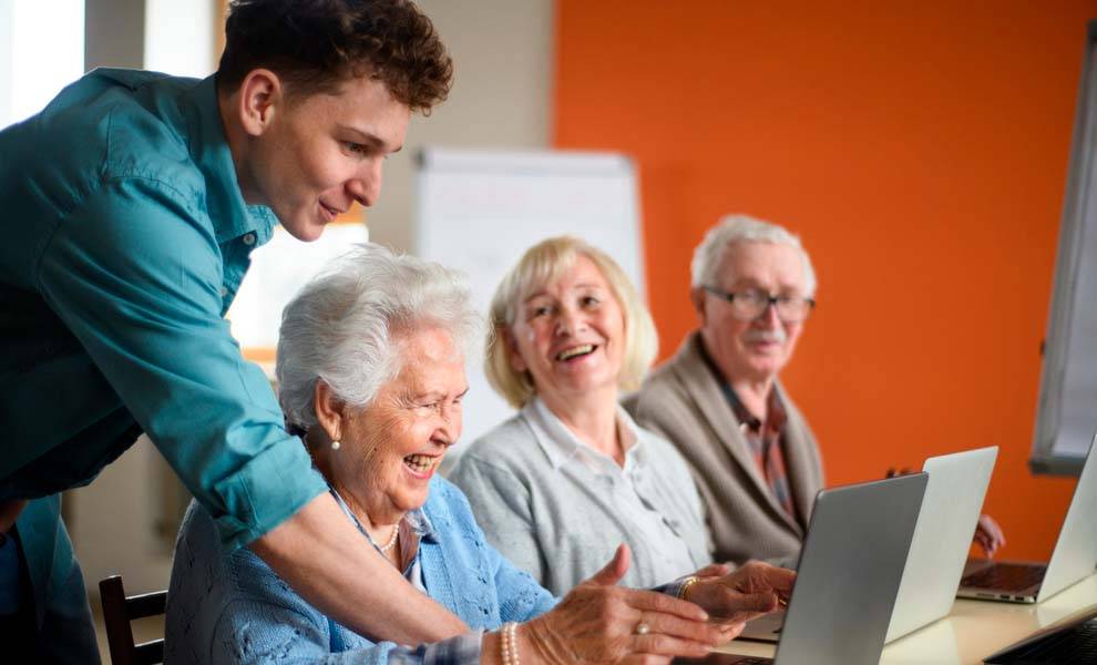 A man and woman smile at each other while viewing a laptop screen.