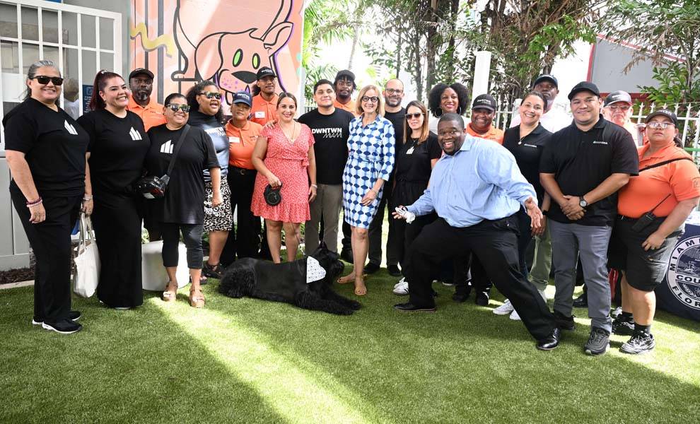 A diverse group of individuals smiling and posing together at the new Downtown Dog Spot.