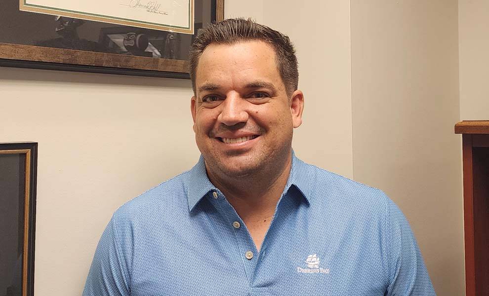 A man named George Hooker is wearing a blue shirt smiling warmly.