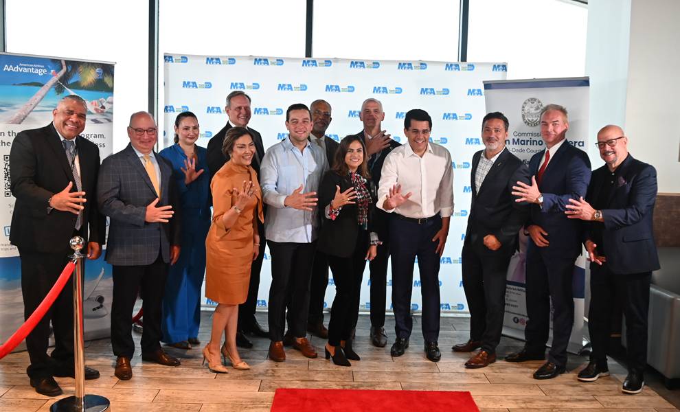 Un grupo diverso de personas posa juntas frente a una alfombra roja vibrante.