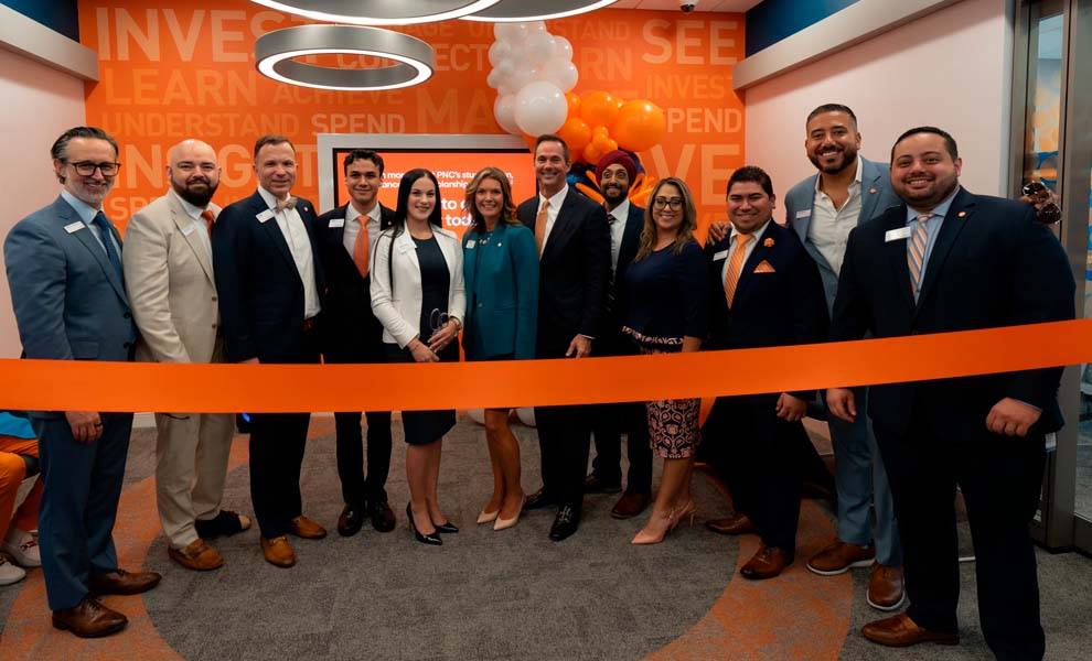 A diverse group of individuals stands proudly in front of a large ribbon, ready to celebrate a significant opening event.