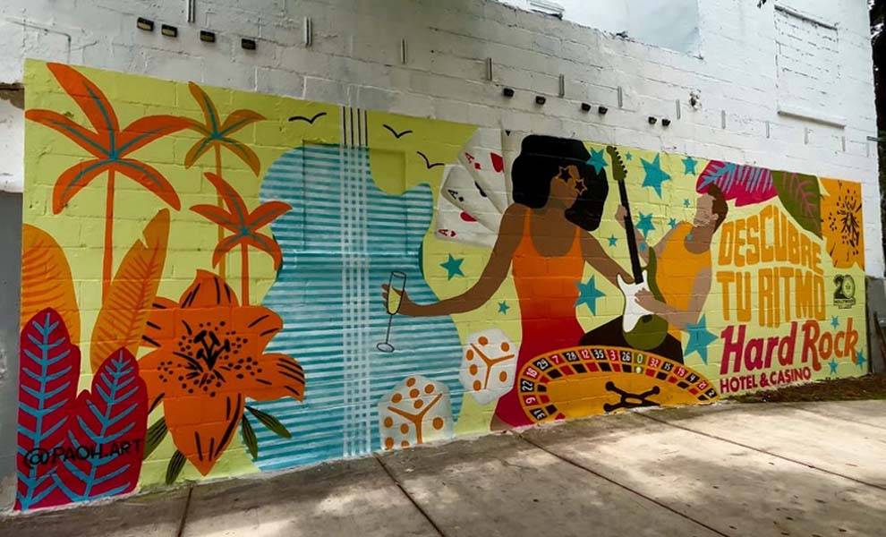 Un mural vibrante que representa a una mujer bailando y a un hombre tocando una guitarra en el costado de un edificio.