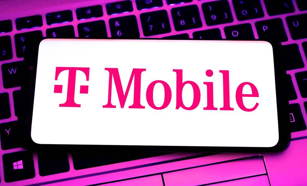 T-Mobile logo on cell phone screen sitting on top of a computer keyboard.