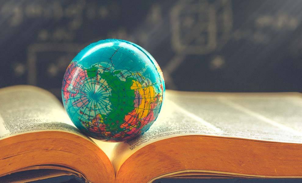 Un libro abierto con un globo terráqueo emergiendo de sus páginas.