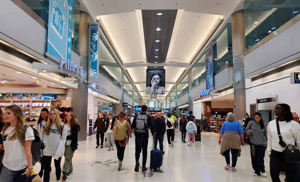 Una terminal de aeropuerto concurrida y llena de viajeros caminando con su equipaje.
