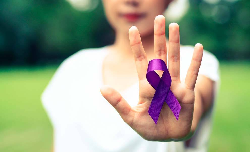 Una mujer muestra con orgullo una cinta morada, que simboliza la concienciación y el apoyo contra la violencia doméstica.