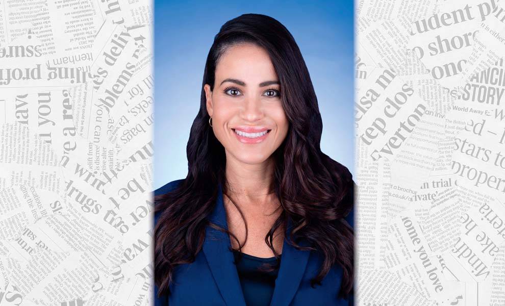 A woman in a blue suit smiles confidently in front of various newspaper headlines.