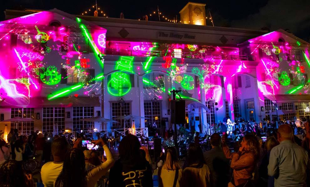 A large crowd gathers in front of a brightly lit building at the Miami Beach Festival of Lights.