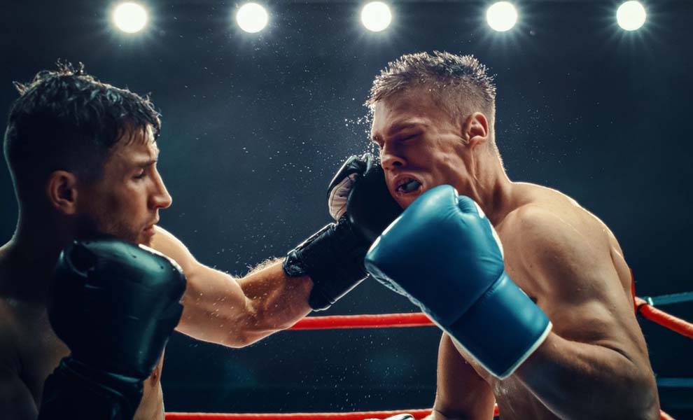 Dos boxeadores se enfrentan en un feroz combate dentro del ring de boxeo.