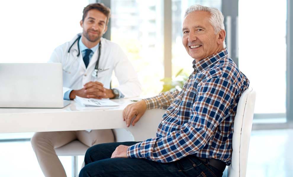A man seated at a desk engaged in a discussion with a doctor.