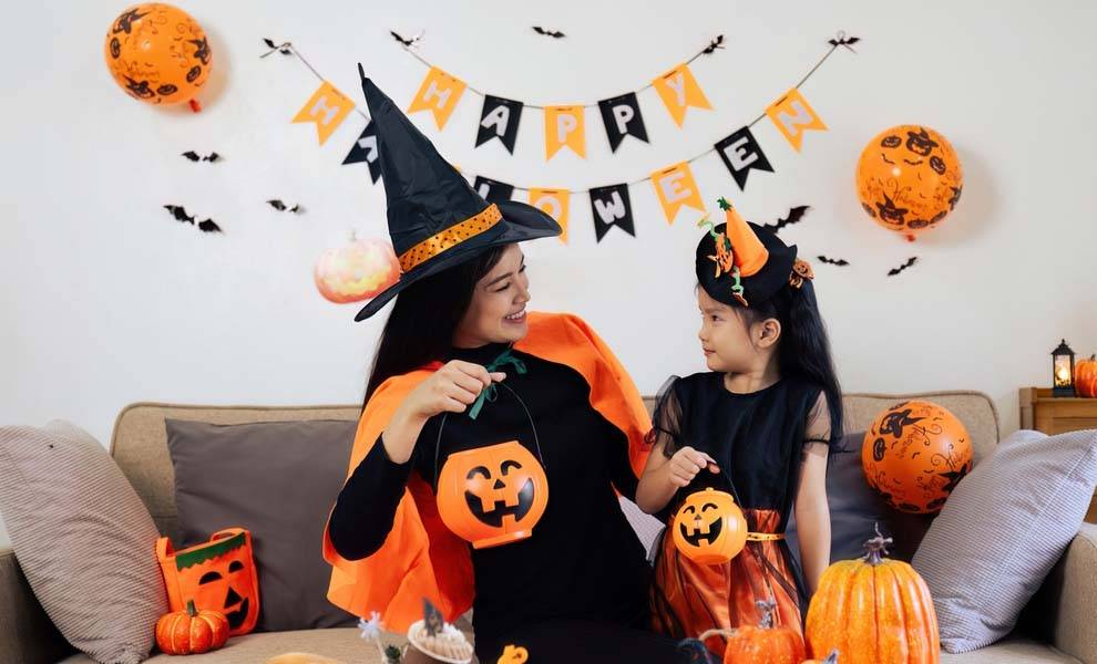Una mujer y un niño alegremente vestidos con coloridos disfraces de Halloween.