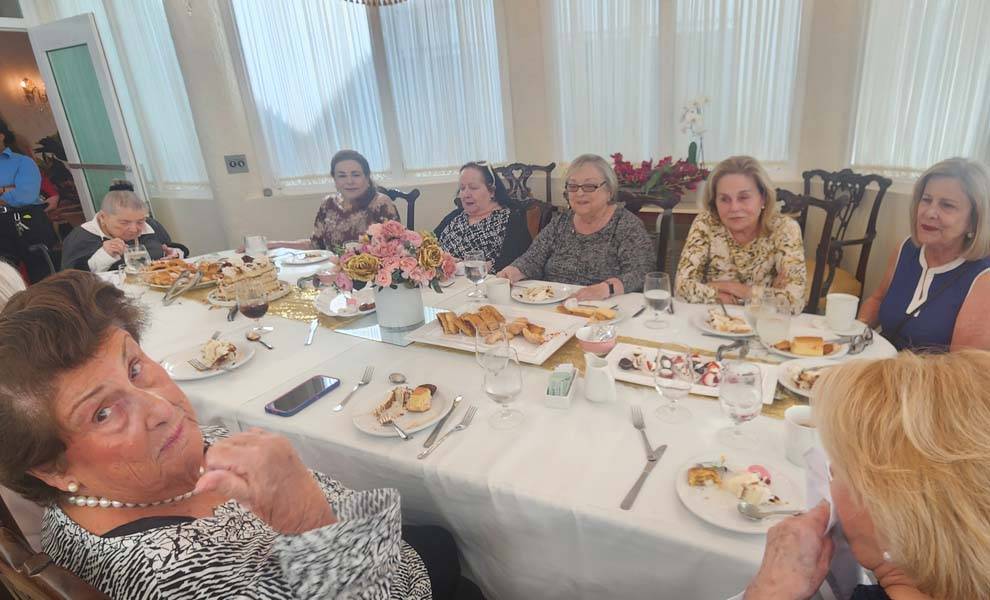 Varias mujeres sentadas en una mesa, compartiendo una comida y participando en una animada conversación.