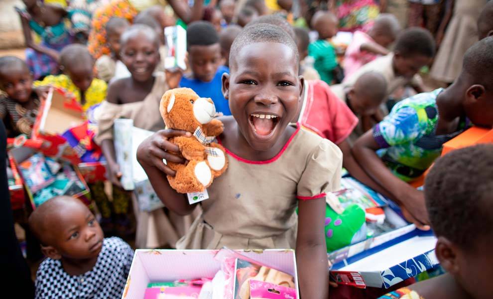 Una niña sonríe de alegría mientras sostiene su amado animal de peluche cerca de su pecho.
