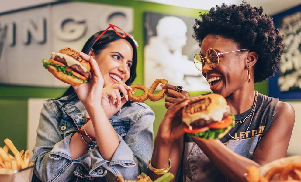 Two women enjoying burgers together at the Flying Cow restaurant in the Seminole Classic Casino.