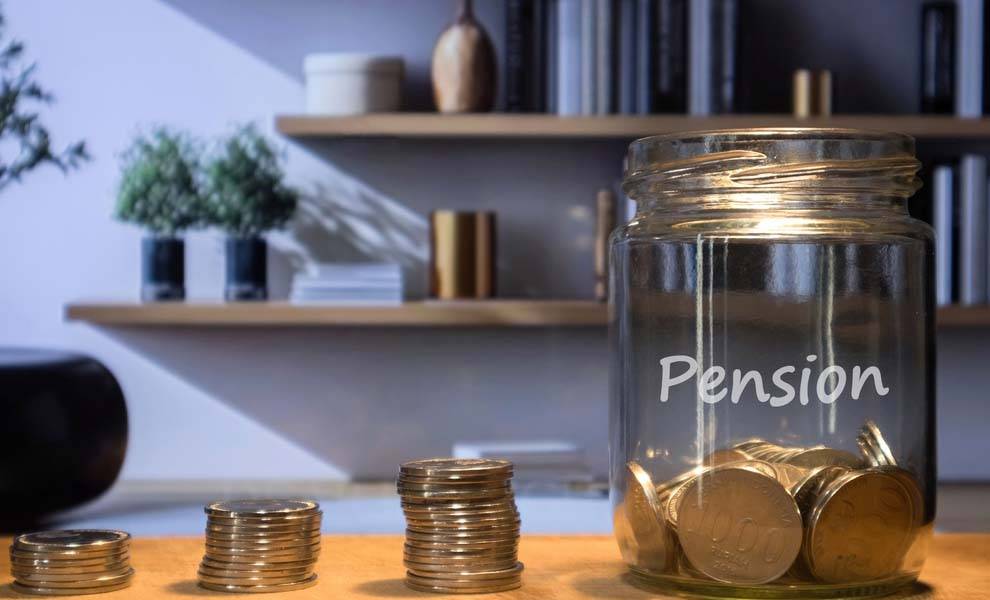 Un escritorio con monedas y un frasco con las palabras pensión.