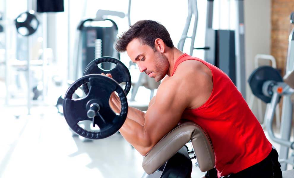 A man performing a weightlifting exercise in a gym.