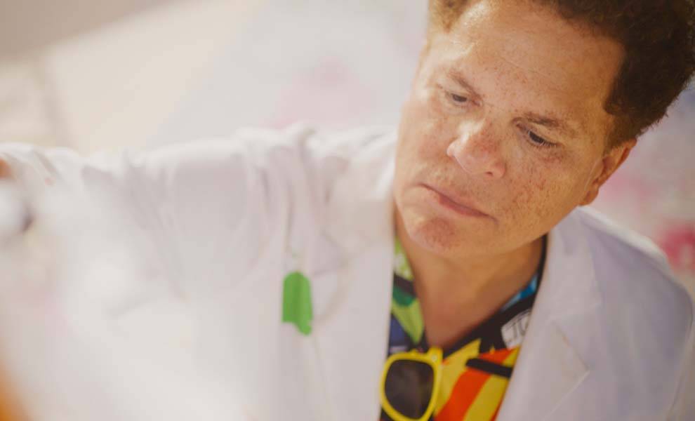 Artist Romero Britto in his studio with a white jacket and colorful shirt.