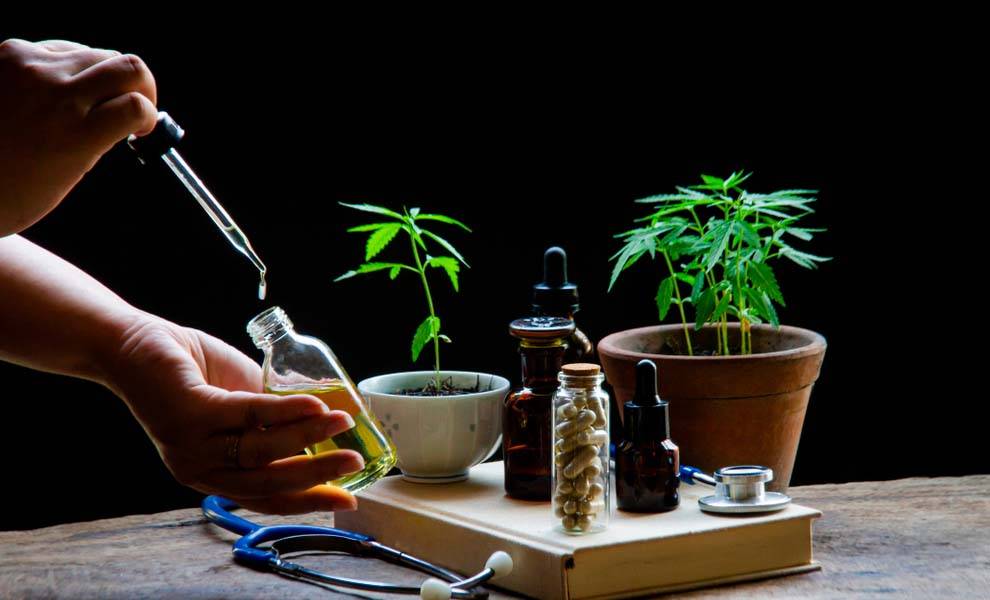 Una persona vierte con cuidado aceite en una botella de cannabis, mostrando el proceso de infusión de aceite para uso terapéutico.