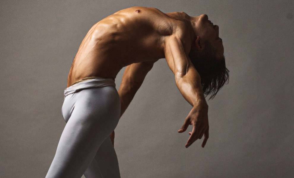 A male dancer performs gracefully, wearing white pants at the Men Who Dance Festival.