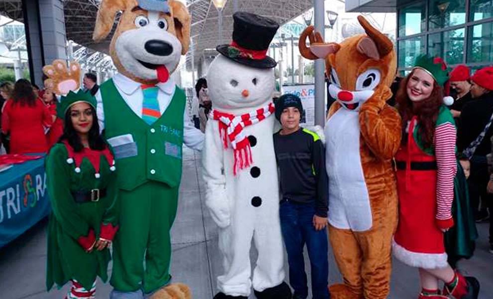 Una reunión festiva de personas vestidas con coloridos trajes navideños en Winter Wonderland de Tri-Rail.